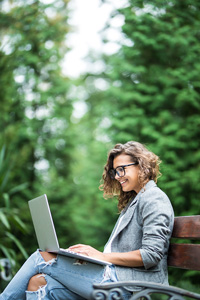 a woman sitting on a bench with a laptop