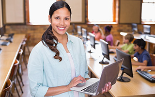 Female teacher in classroom holding a laptop